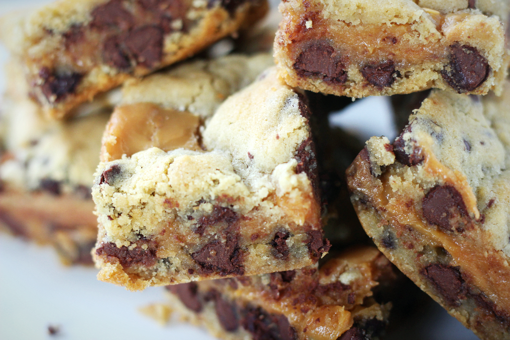 Close up view of a chocolate chip caramel bar packed with chocolate chips and gooey caramel.