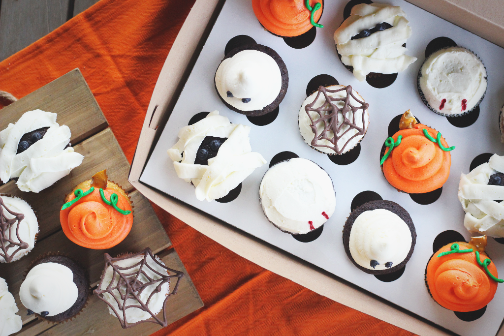 overhead view of a variety of Halloween themed cupcakes like ghost, spider, pumpkin, and mummy