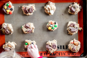 overhead view of a baking sheet with cokie dough balls filled with leftover halloween candy