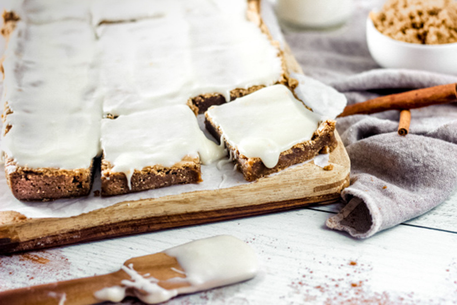 Shot of cinnamon roll bars with cream cheese frosting dripping over the sides
