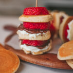 Close up of mini pancake skewers layered with Nutella and fresh strawberries on a stick