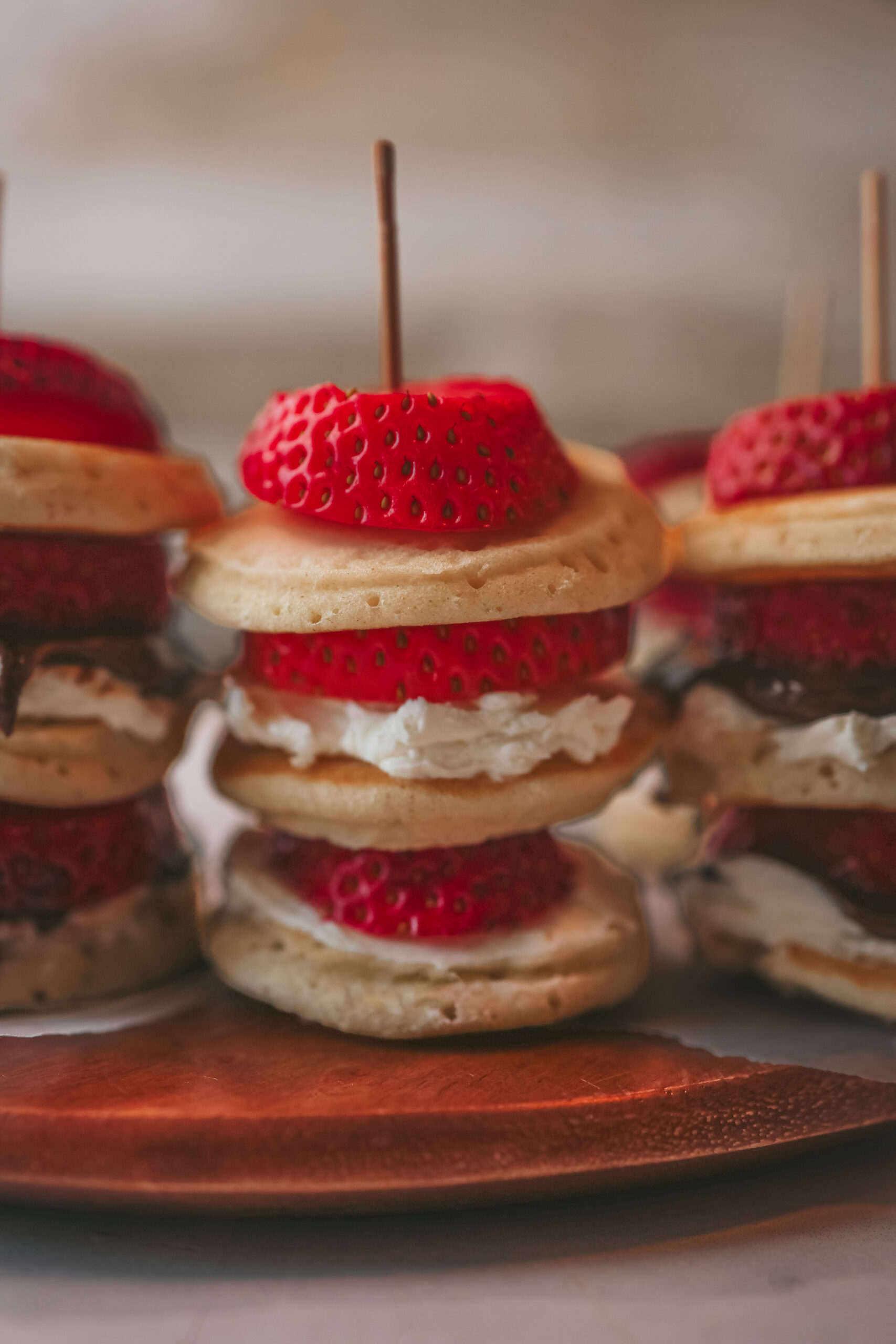 Close up of mini pancake skewers layered with Nutella and fresh strawberries on a stick