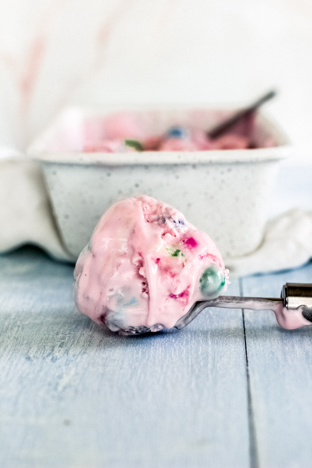 A scoop of a pink bubblegum ice cream recipe sits on a table