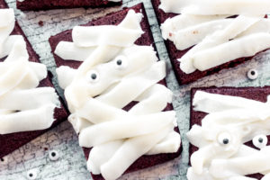 overhead view of a brownie topped with white frosting swoops to look like a mummy