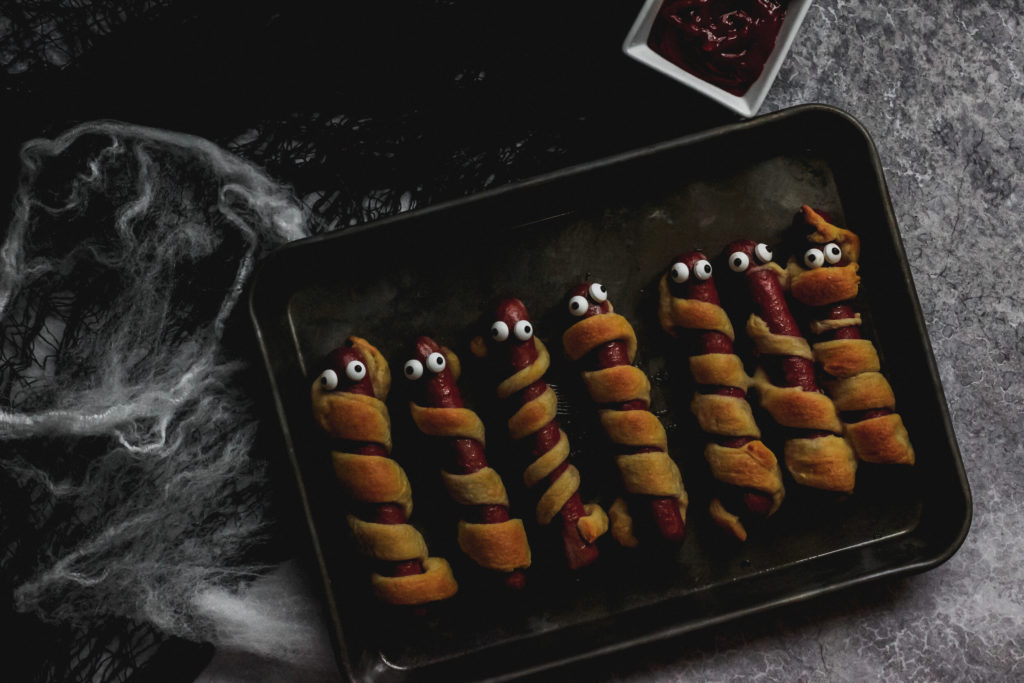 overhead view of a hot dog wrapped in crescent roll dough to look like a mummy