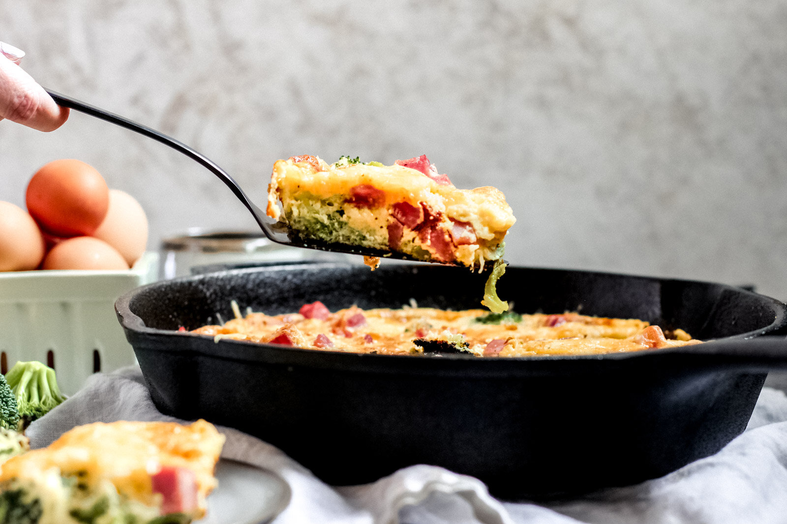 Side view of a cast iron pan with a piece of the frittata being lifted out