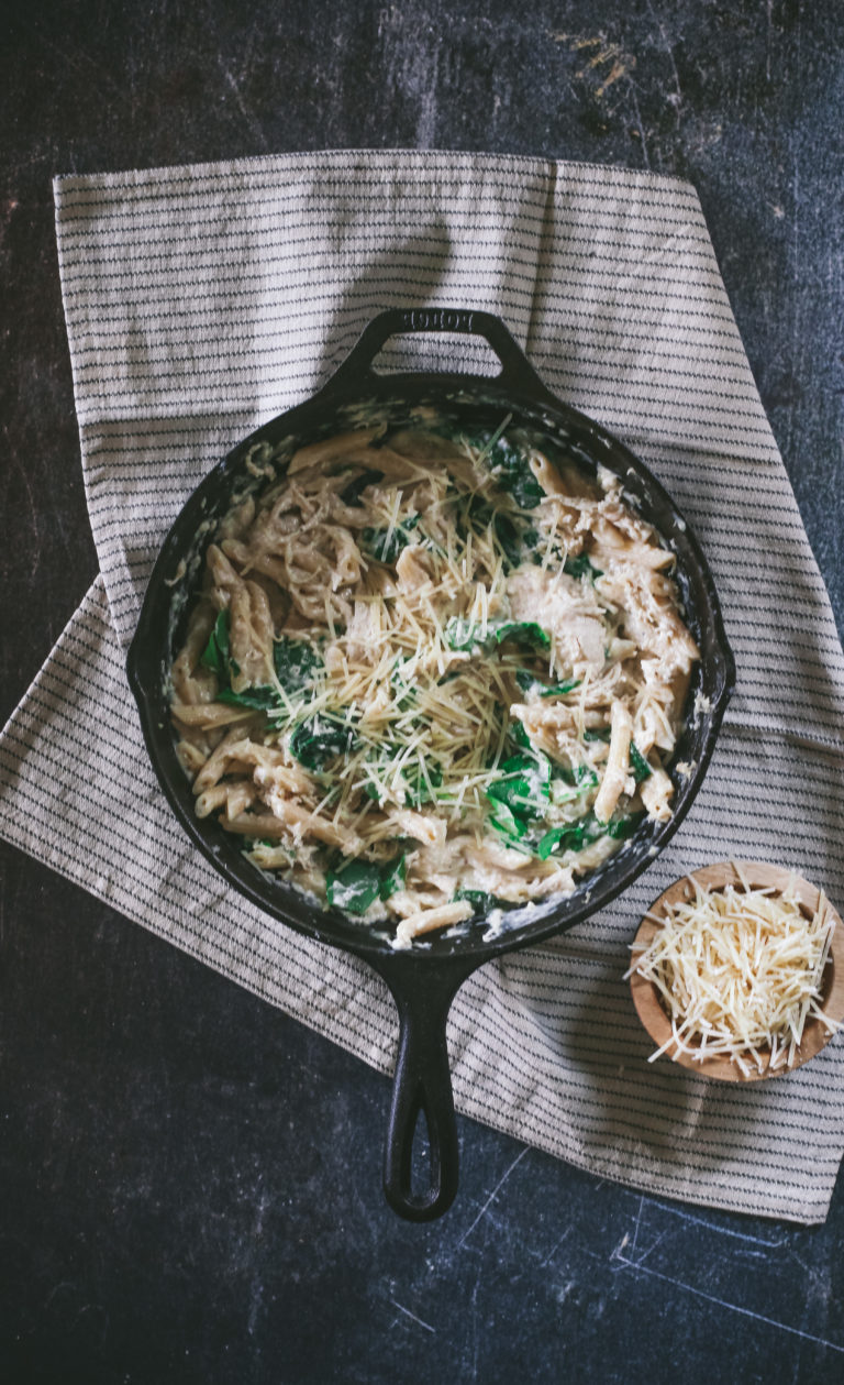 Overhead look at a skillet filled with pasta and creamy sauce and cheese.
