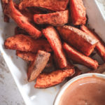 Overhead view of sweet potato wedges in the air fryer and dipping sauce