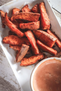 Overhead view of sweet potato wedges in the air fryer and dipping sauce