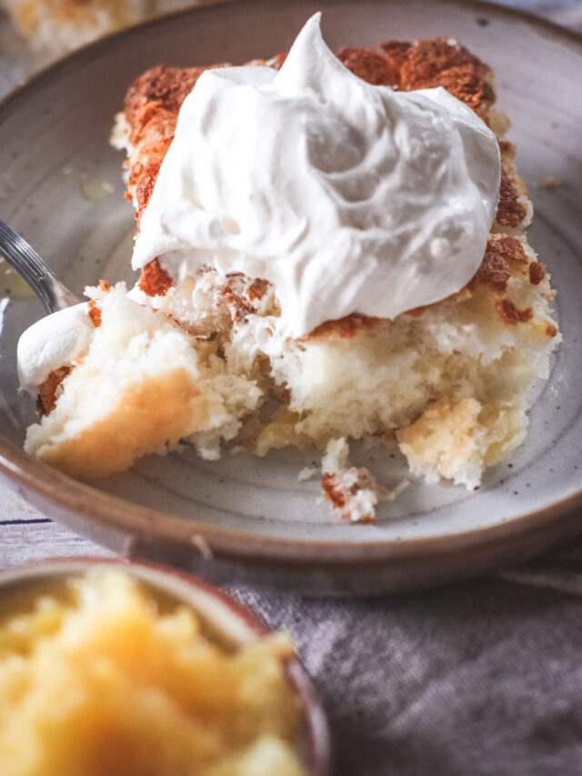 Straight on view of a piece of pineapple cake with whip cream on top