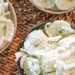 overhead view of a bowl nof creamy cucumber salad and onions