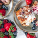 overhead view of a plate of berries and cream baked french toast and a cream cheese drizzle