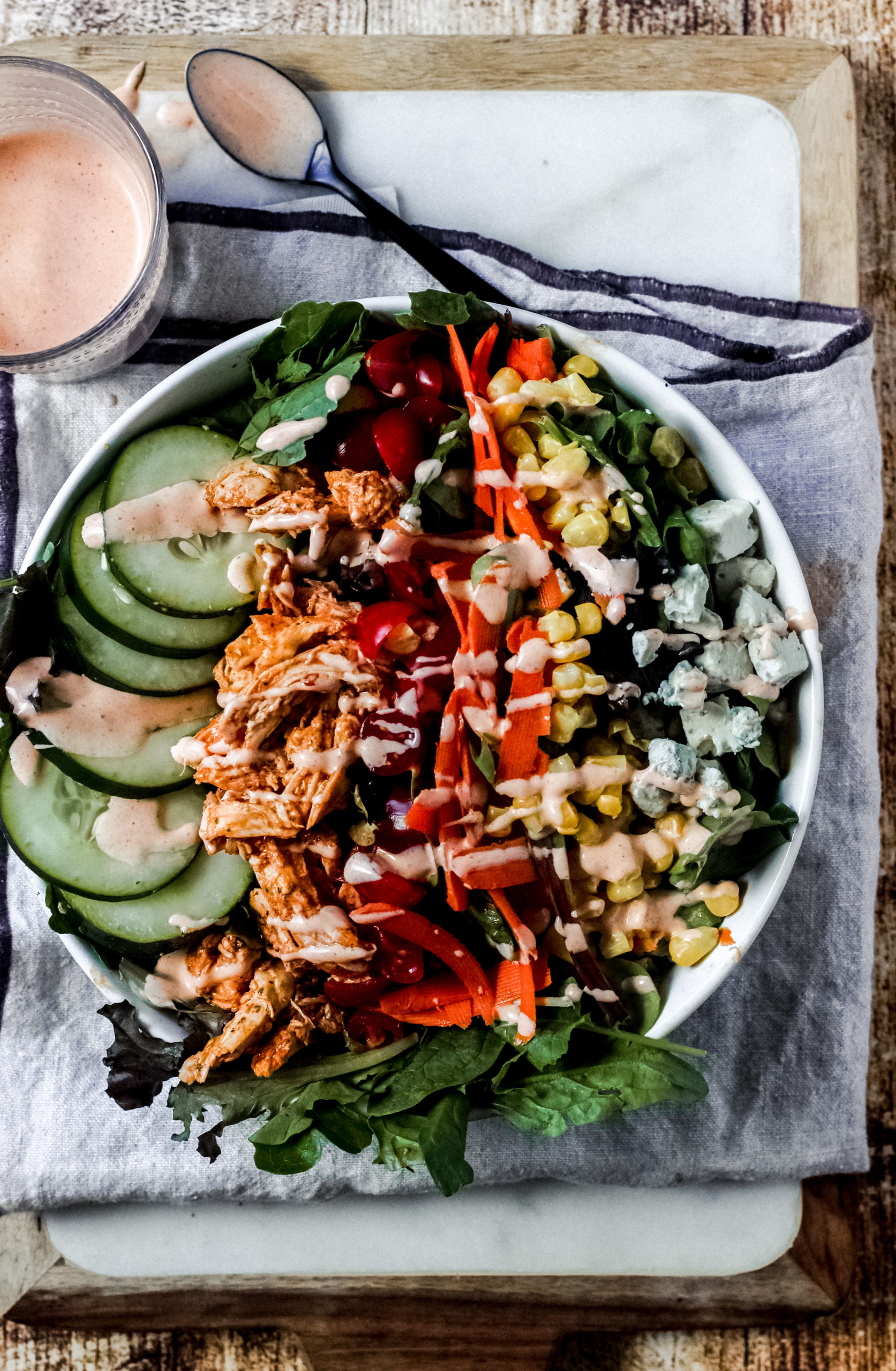 overhead view of a buffalo chicken salad with a colorful bowl of veggies