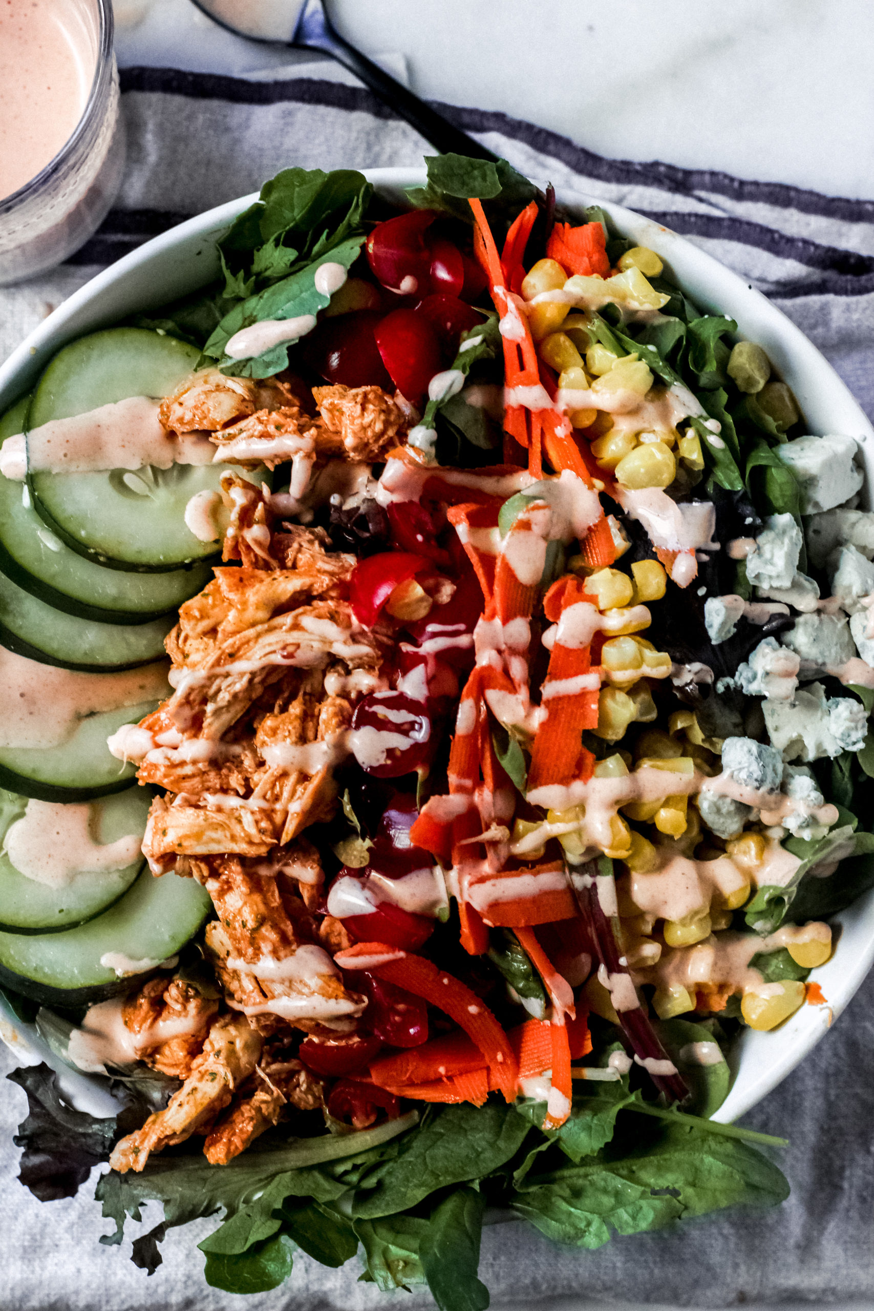 overhead view of a buffalo chicken salad with a colorful bowl of veggies