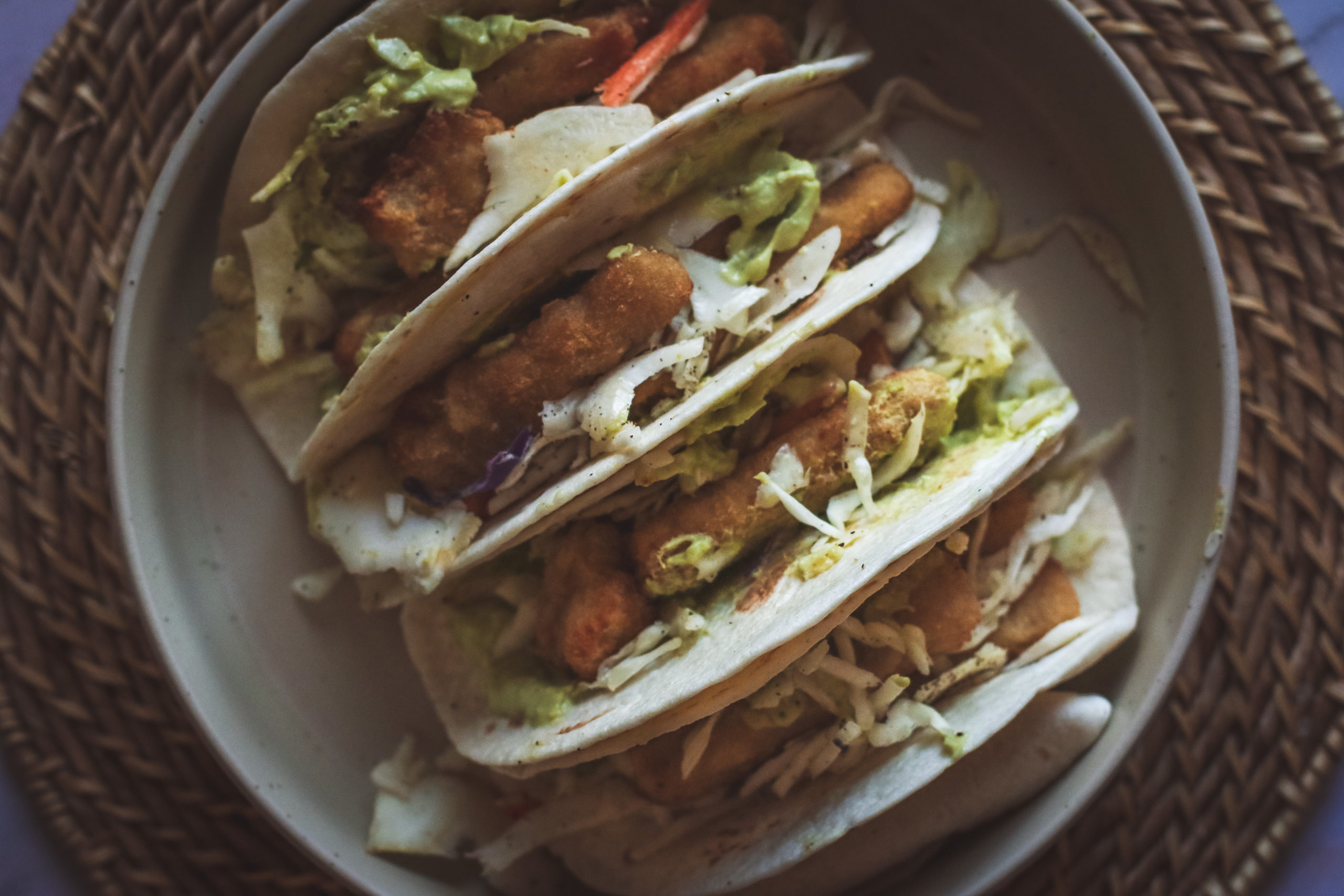 overhead view of fish stick tacos filled with slaw and avocado sauce