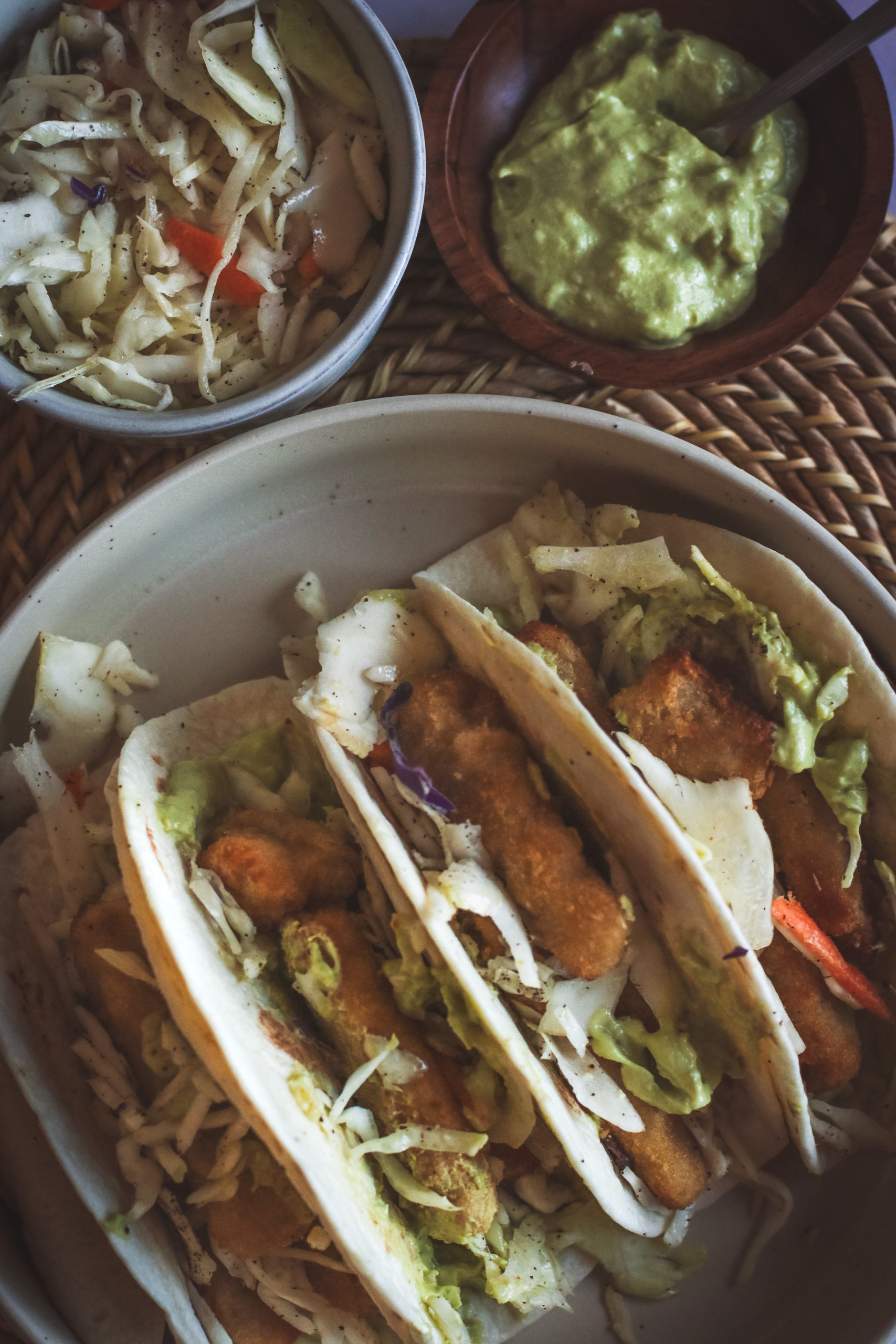 overhead view of fish stick tacos filled with slaw and avocado sauce