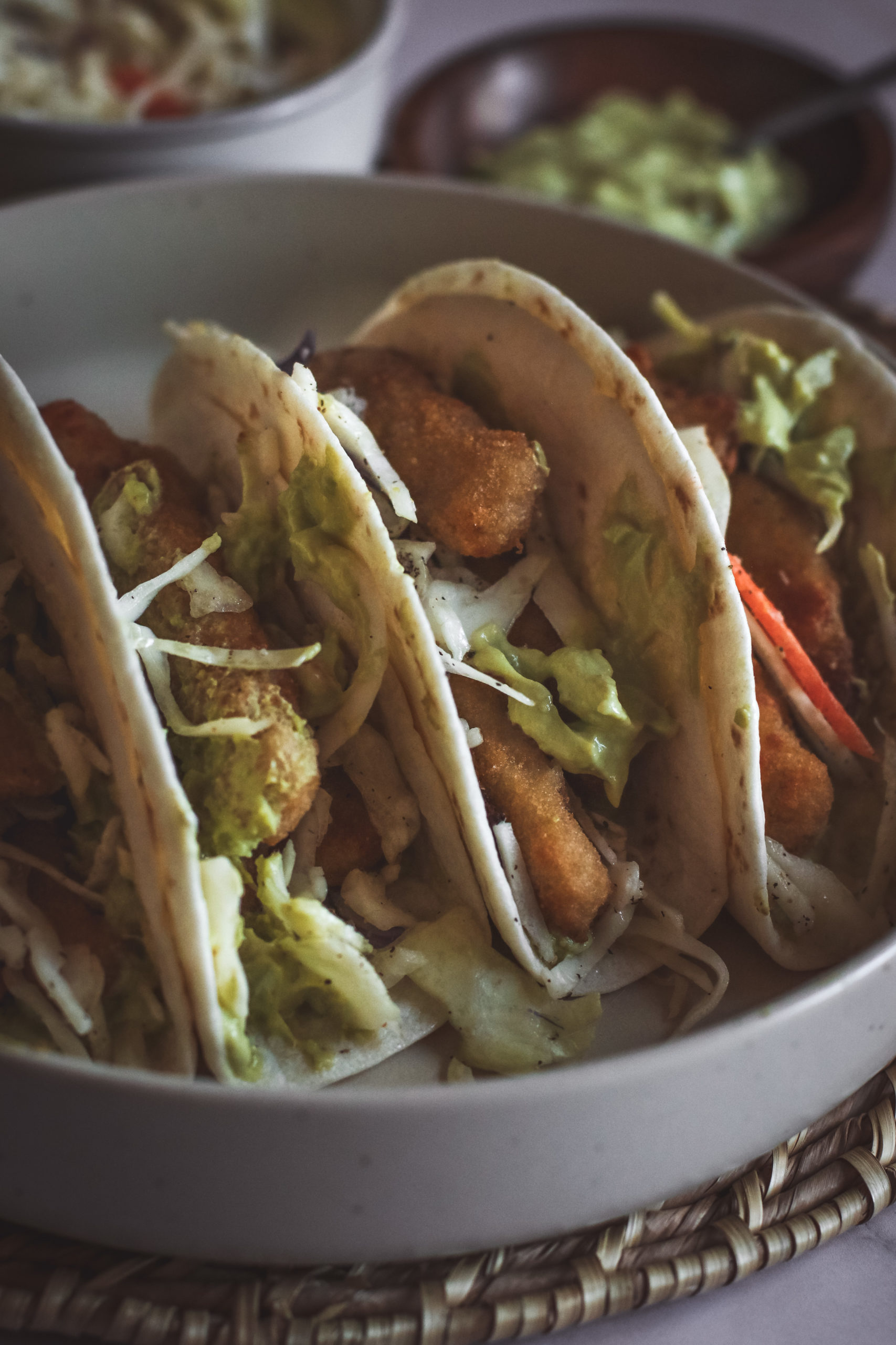 straight on view of fish stick tacos filled with slaw and avocado sauce