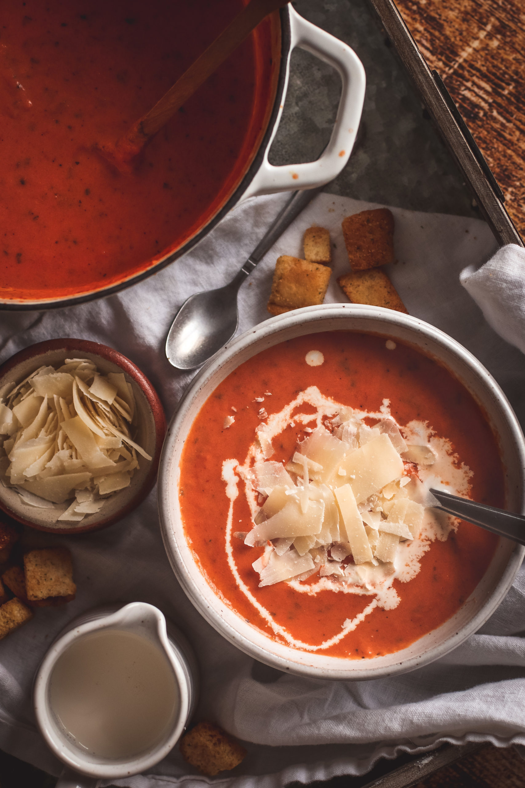 Overhead view of a bowl of creamy tomato basil soup with croutons and cheese