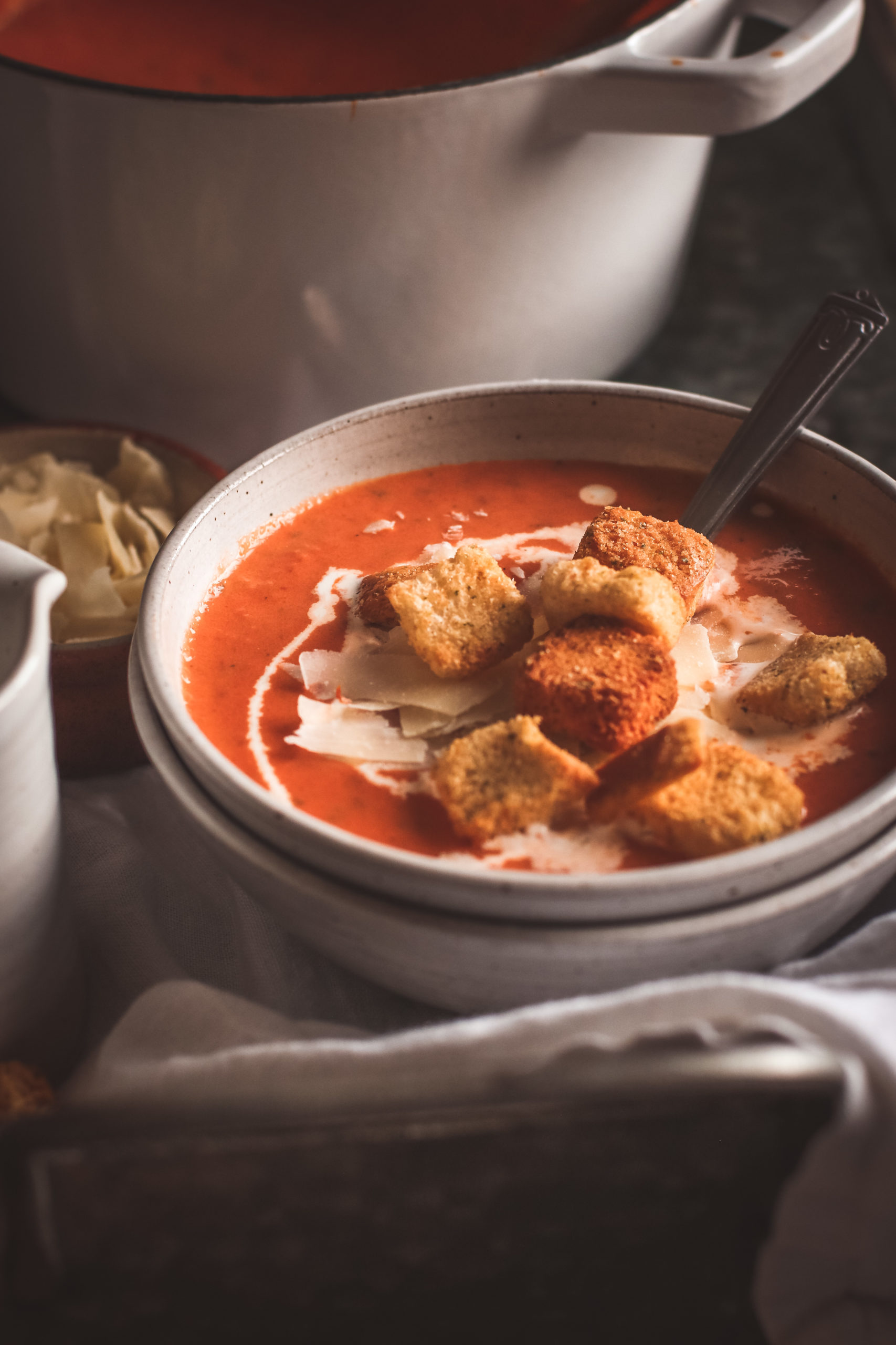 Straight on view of a bowl of creamy tomato basil soup with croutons and cheese