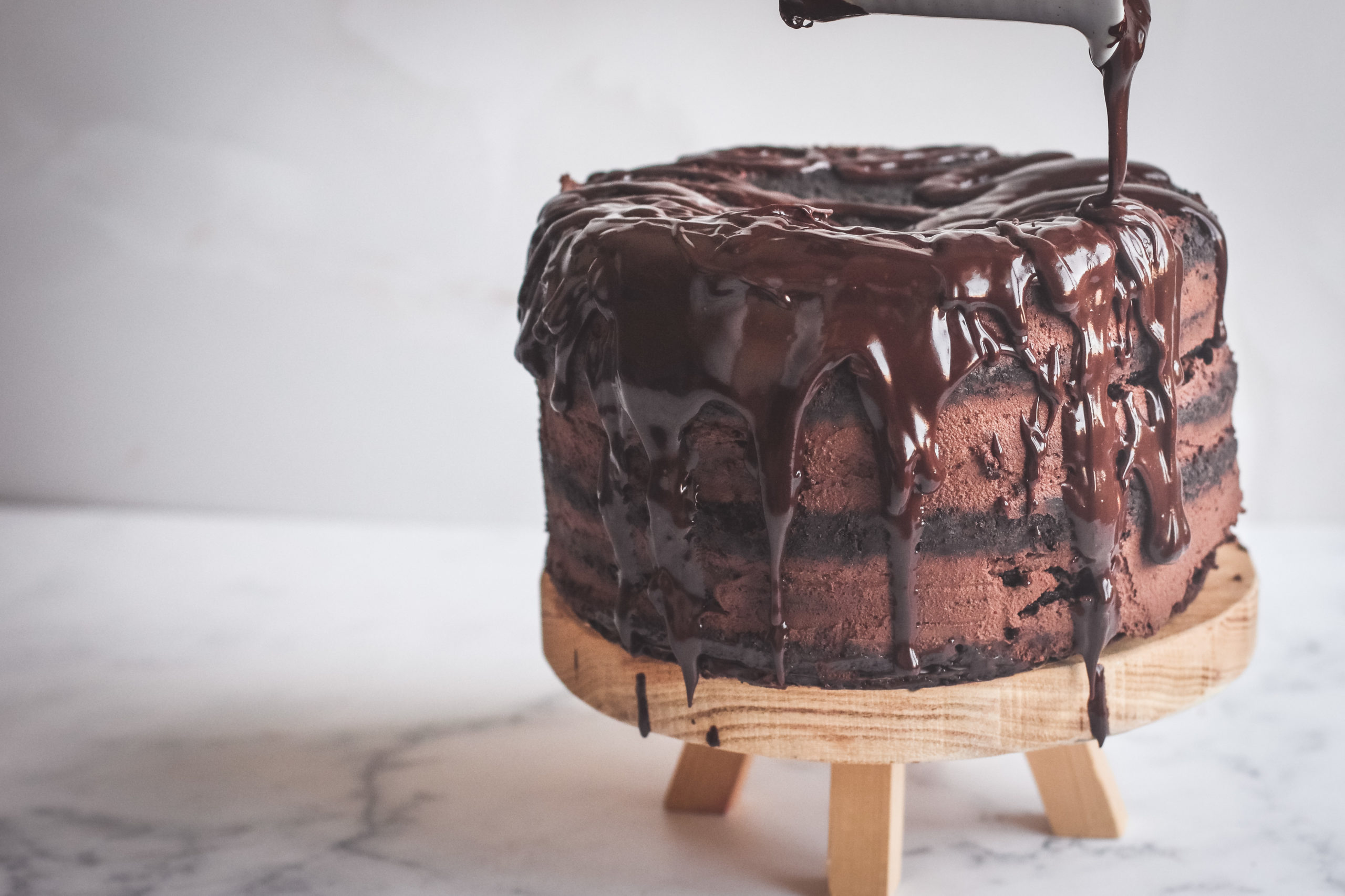 straight view of a layered dark chocolate mousse cake with drizzles of chocolate ganache