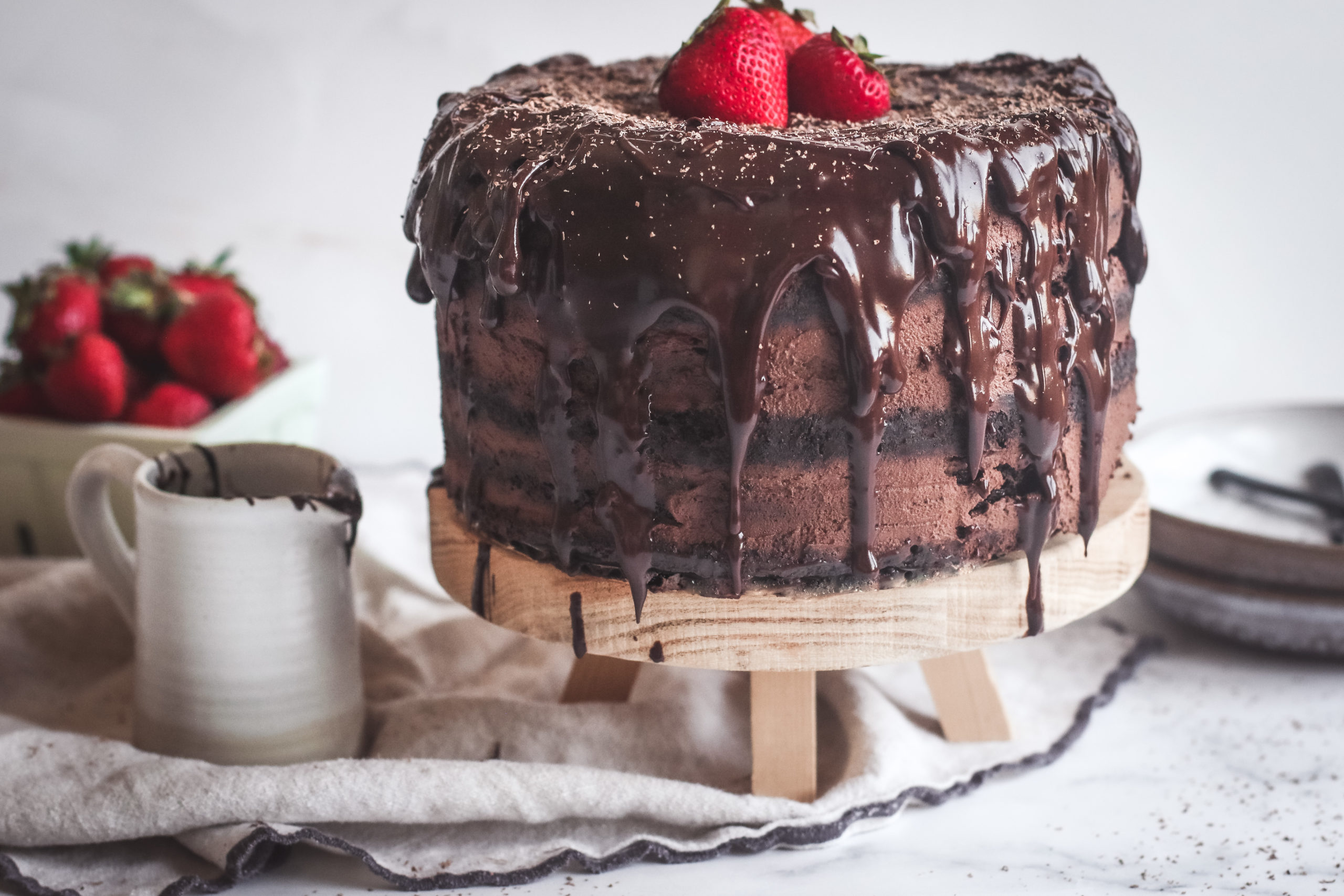 straight view of a layered dark chocolate mousse cake with drizzles of chocolate ganache