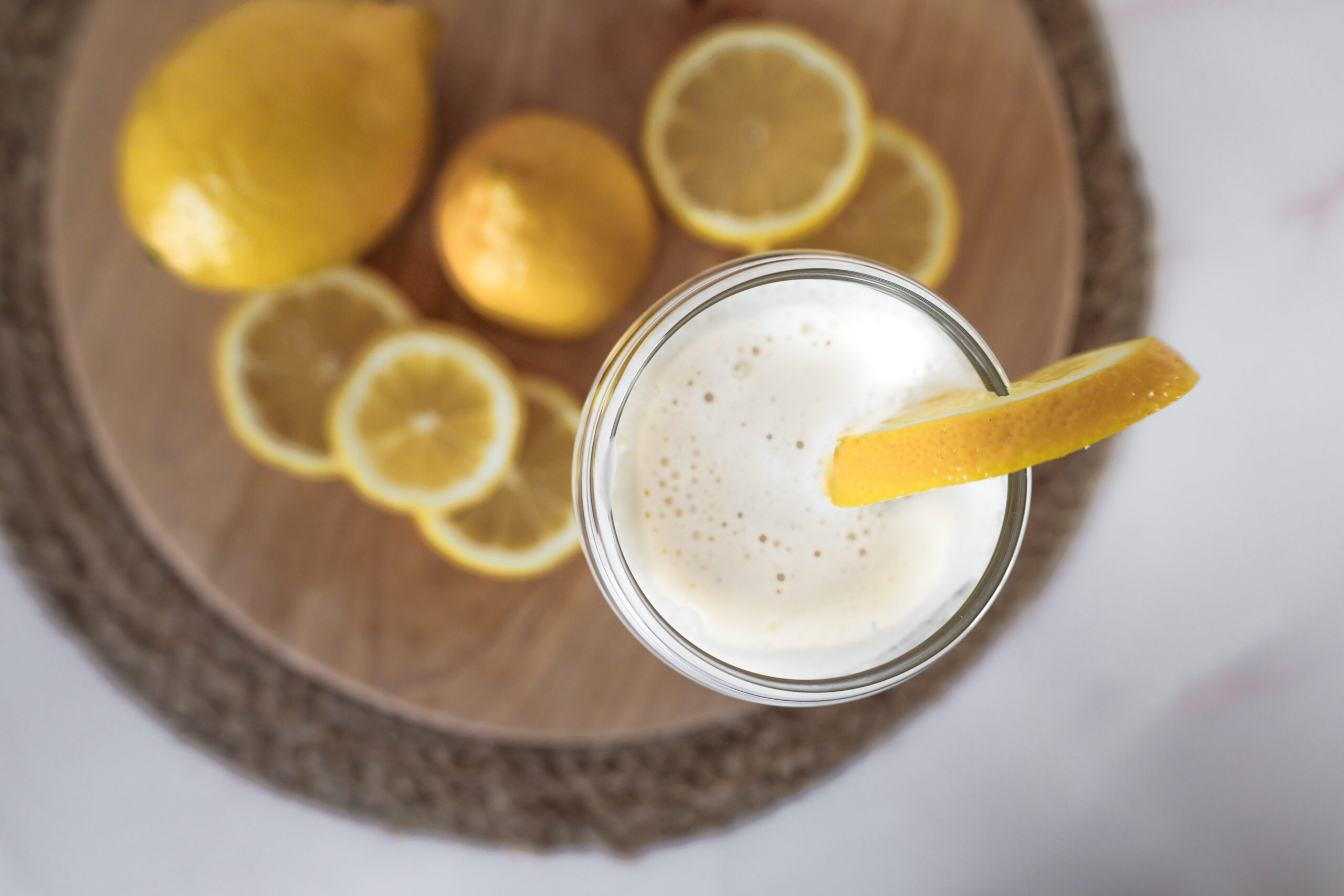 over top view of a cup of creamy lemonade, lemon slices and ice cream.