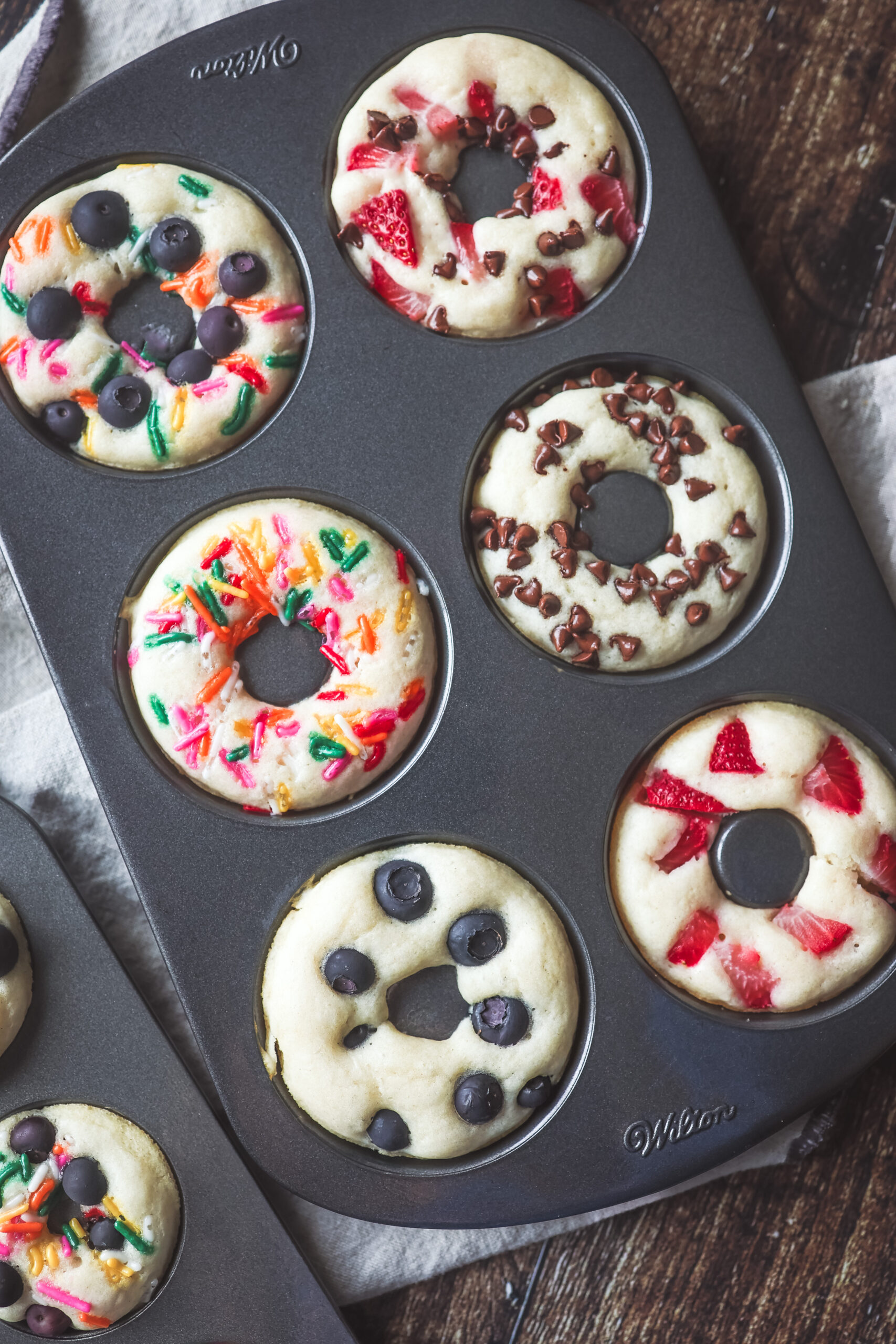 Overhead look at a pan of pancake donuts with fruit and sprinkles