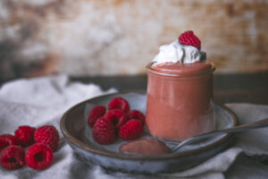 Jar of cottage cheese chocolate mousse with whipped cream and raspberries