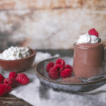 Jar of cottage cheese chocolate mousse with whipped cream and raspberries