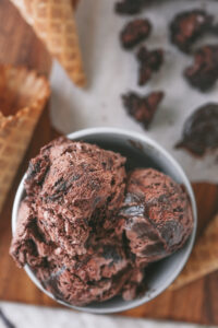 Scoop of rich and creamy no churn chocolate fudge brownie ice cream with chunks of brownie in a white bowl