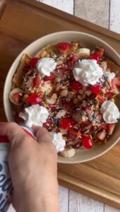 Ice Cream Nachos topped with bananas, strawberries, chocolate syrup, sprinkles and whipped cream.