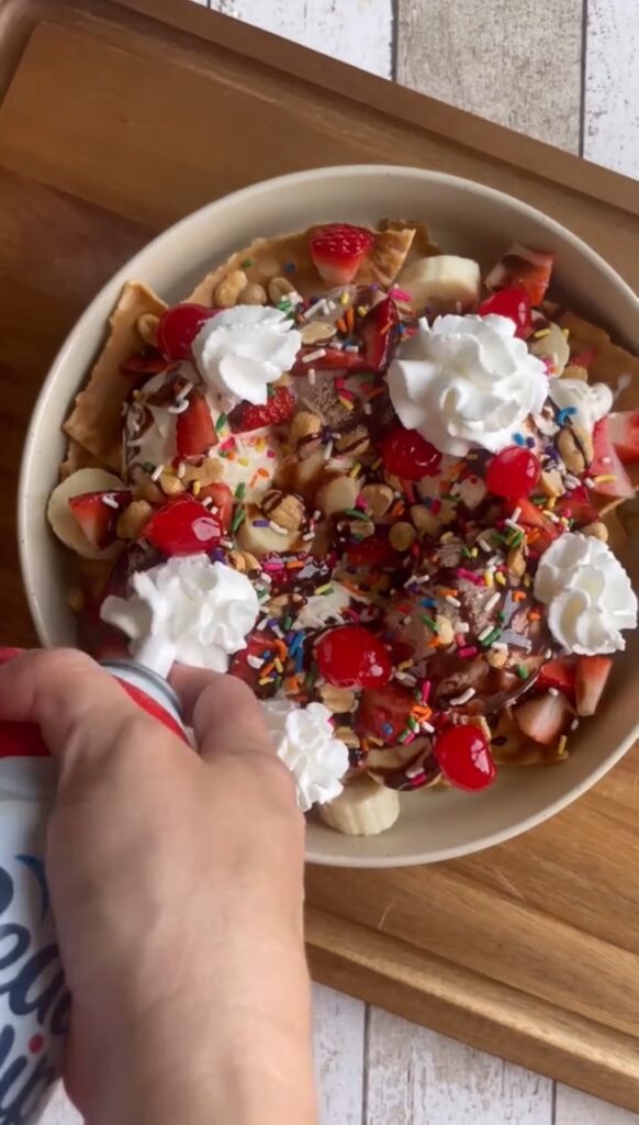 Ice Cream Nachos topped with bananas, strawberries, chocolate syrup, sprinkles and whipped cream.