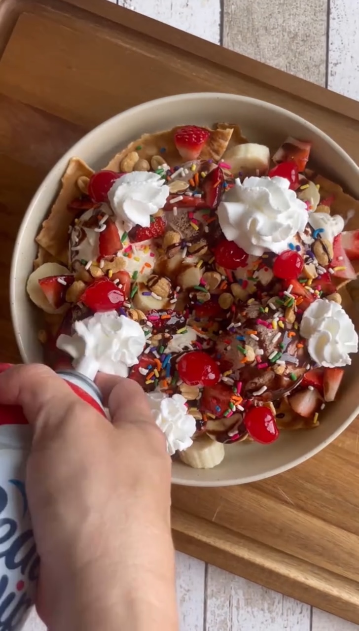Ice Cream Nachos topped with bananas, strawberries, chocolate syrup, sprinkles and whipped cream.