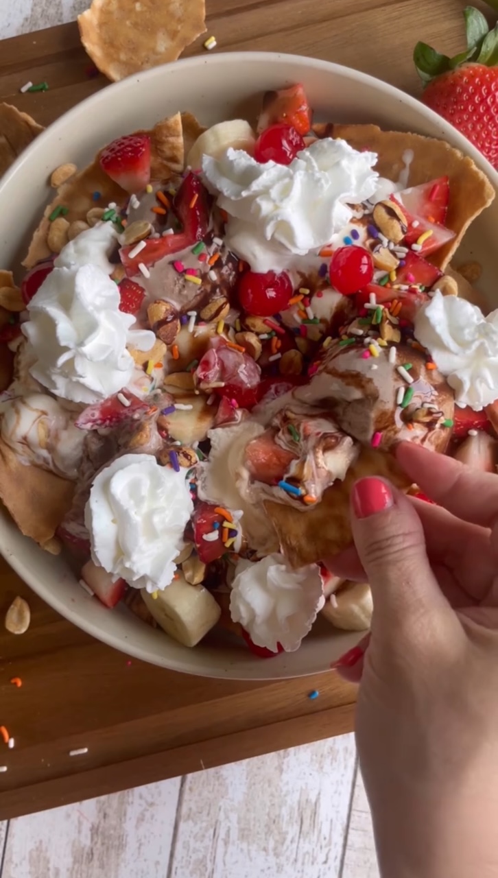 Ice Cream Nachos topped with bananas, strawberries, chocolate syrup, sprinkles and whipped cream.