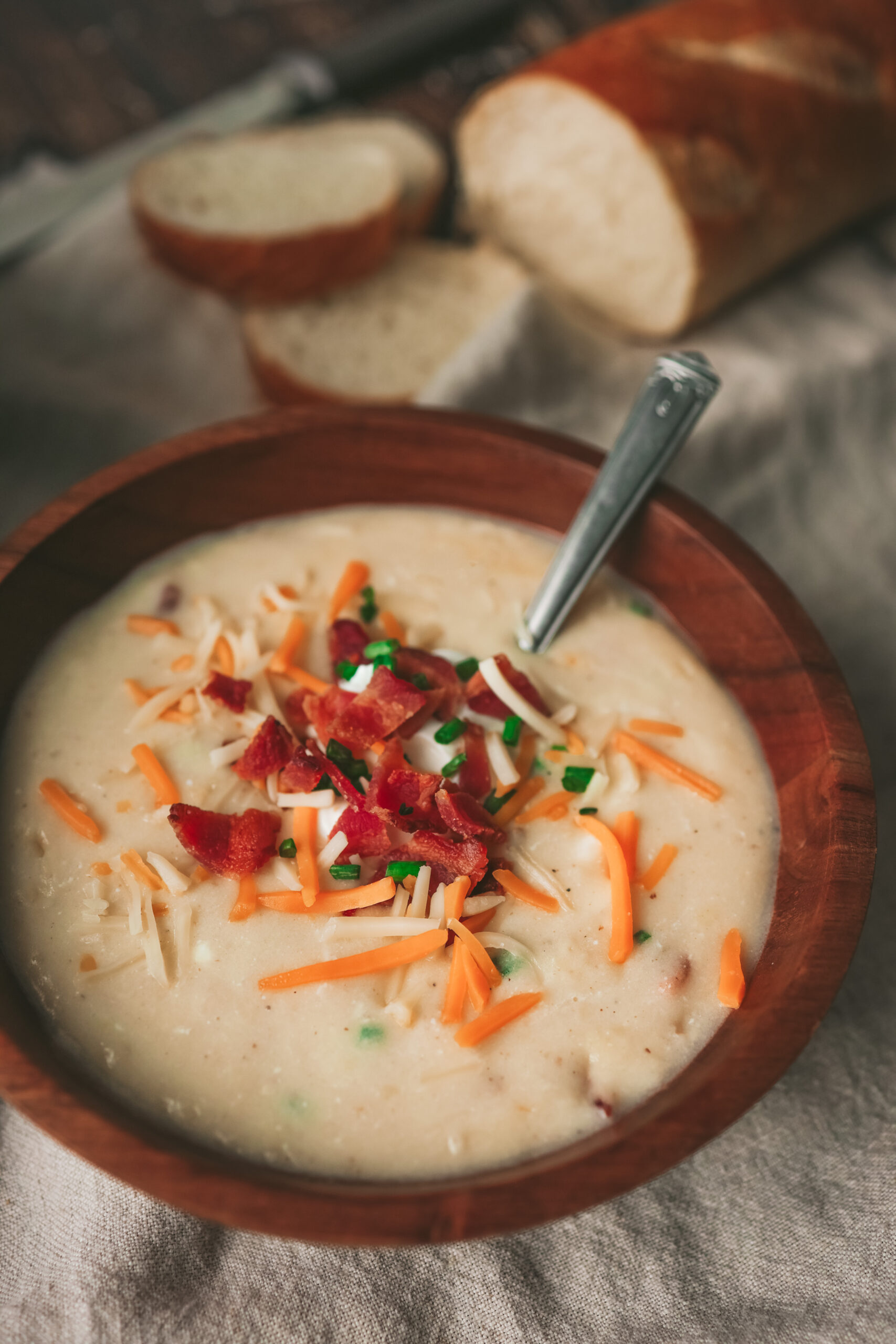 Overhead look at a bowl of creamy potato soup with bacon, chives and cheese