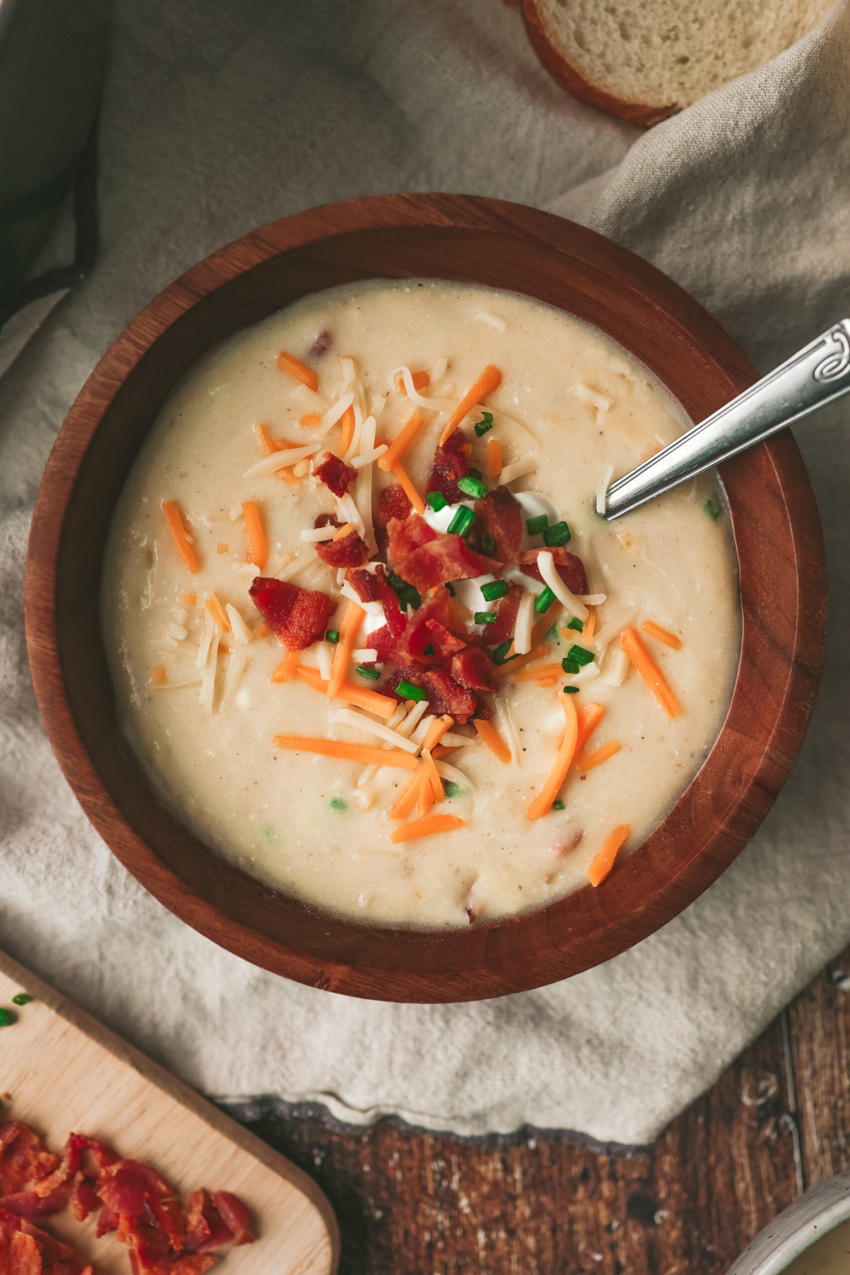 Overhead look at a bowl of creamy potato soup with bacon, chives and cheese