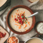 Overhead look at a bowl of creamy potato soup with bacon, chives and cheese