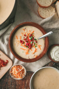Overhead look at a bowl of creamy potato soup with bacon, chives and cheese