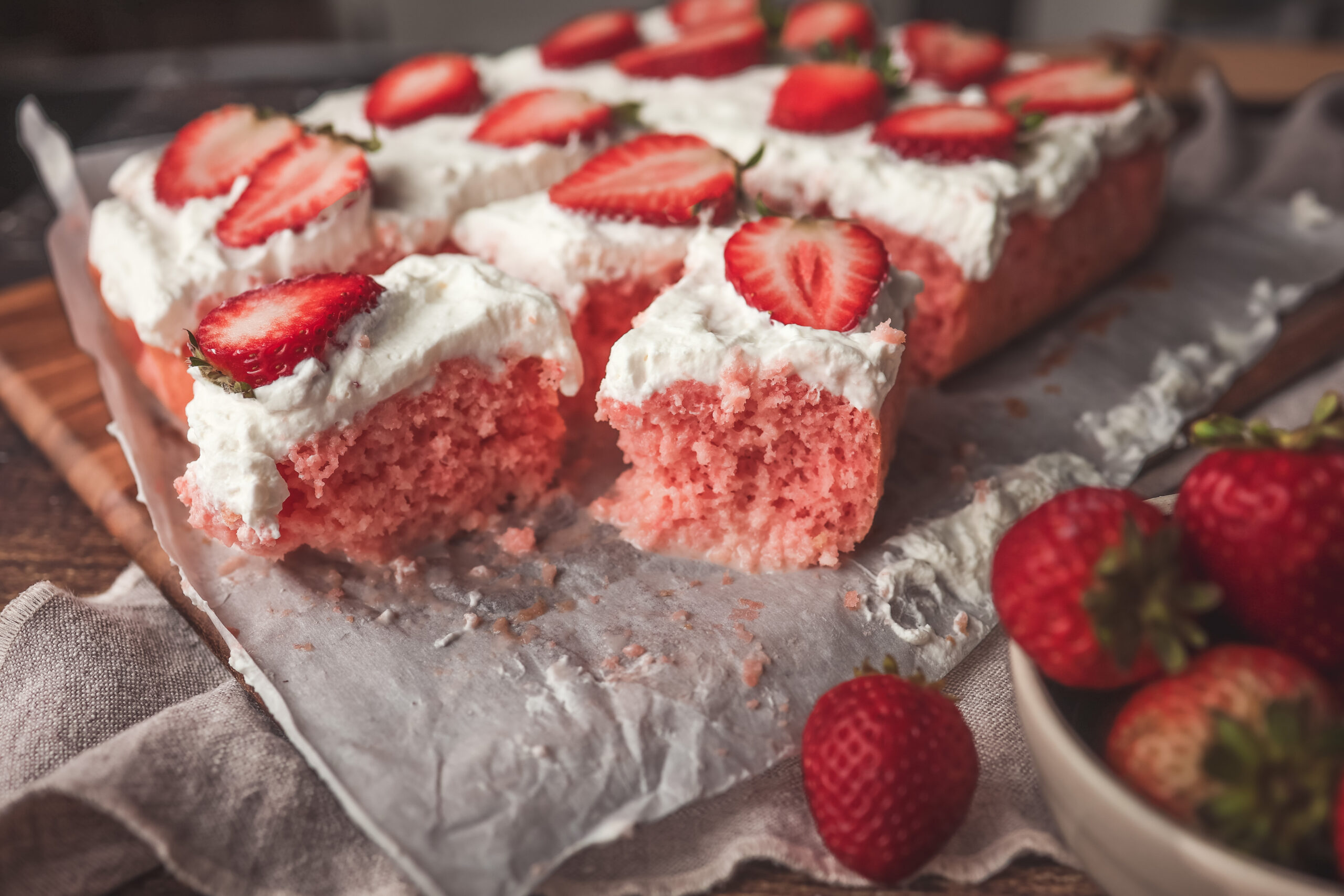 Overhead look of a soft strawberry tres leches cake topped with whipped cream and strawberries.