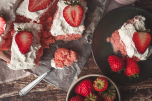 Overhead look of a soft strawberry tres leches cake topped with whipped cream and strawberries.