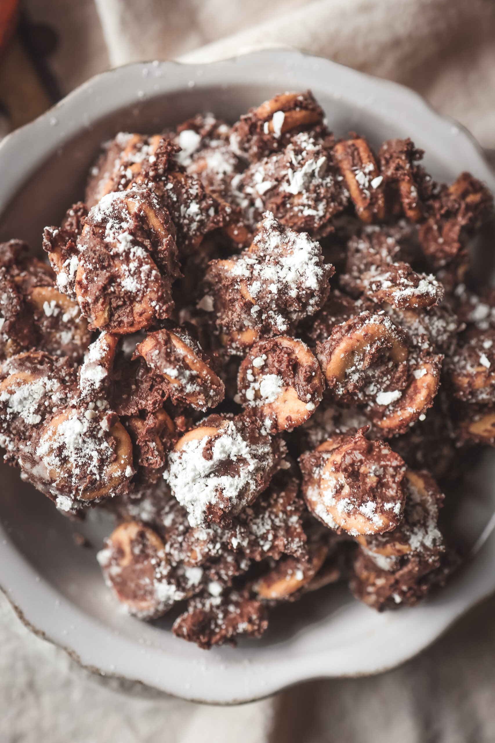 Bowl of Peanut Butter Ritz Cracker Puppy Chow dusted with powdered sugar