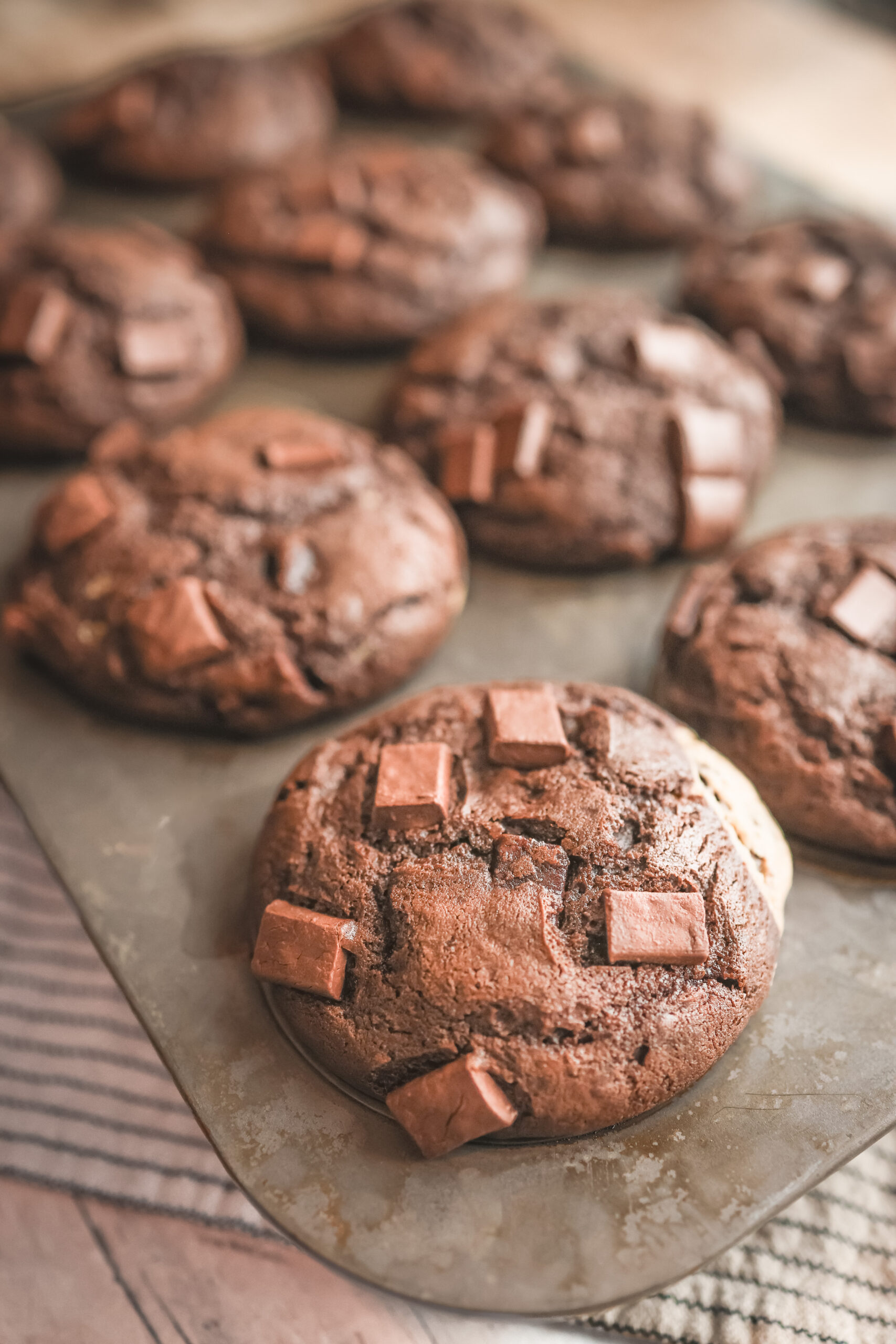 Chocolate peanut butter muffins with chocolate chips and a creamy peanut butter filling in the center, displayed on a plate.