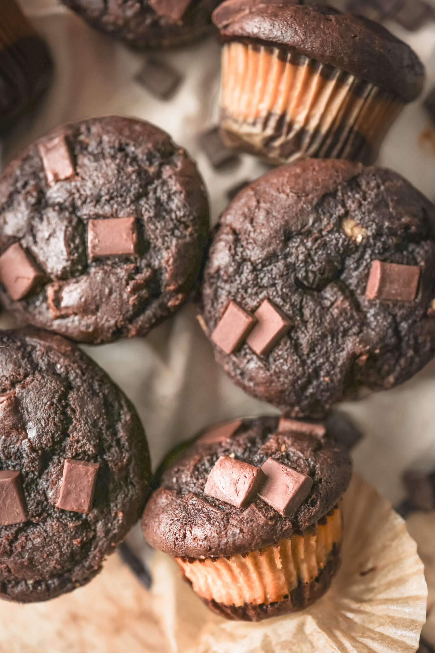 Chocolate peanut butter muffins with chocolate chips and a creamy peanut butter filling in the center, displayed on a plate.