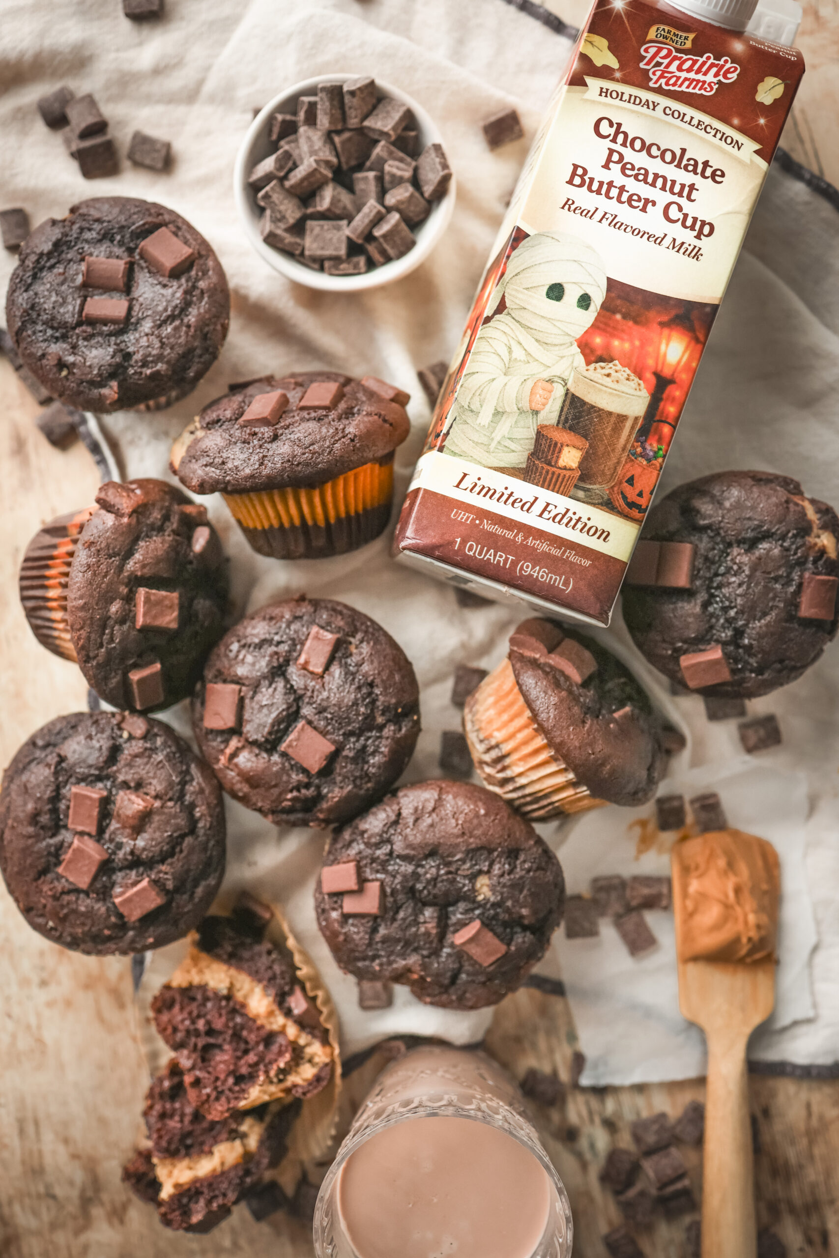 Chocolate peanut butter muffins with chocolate chips and a creamy peanut butter filling in the center, displayed on a plate.