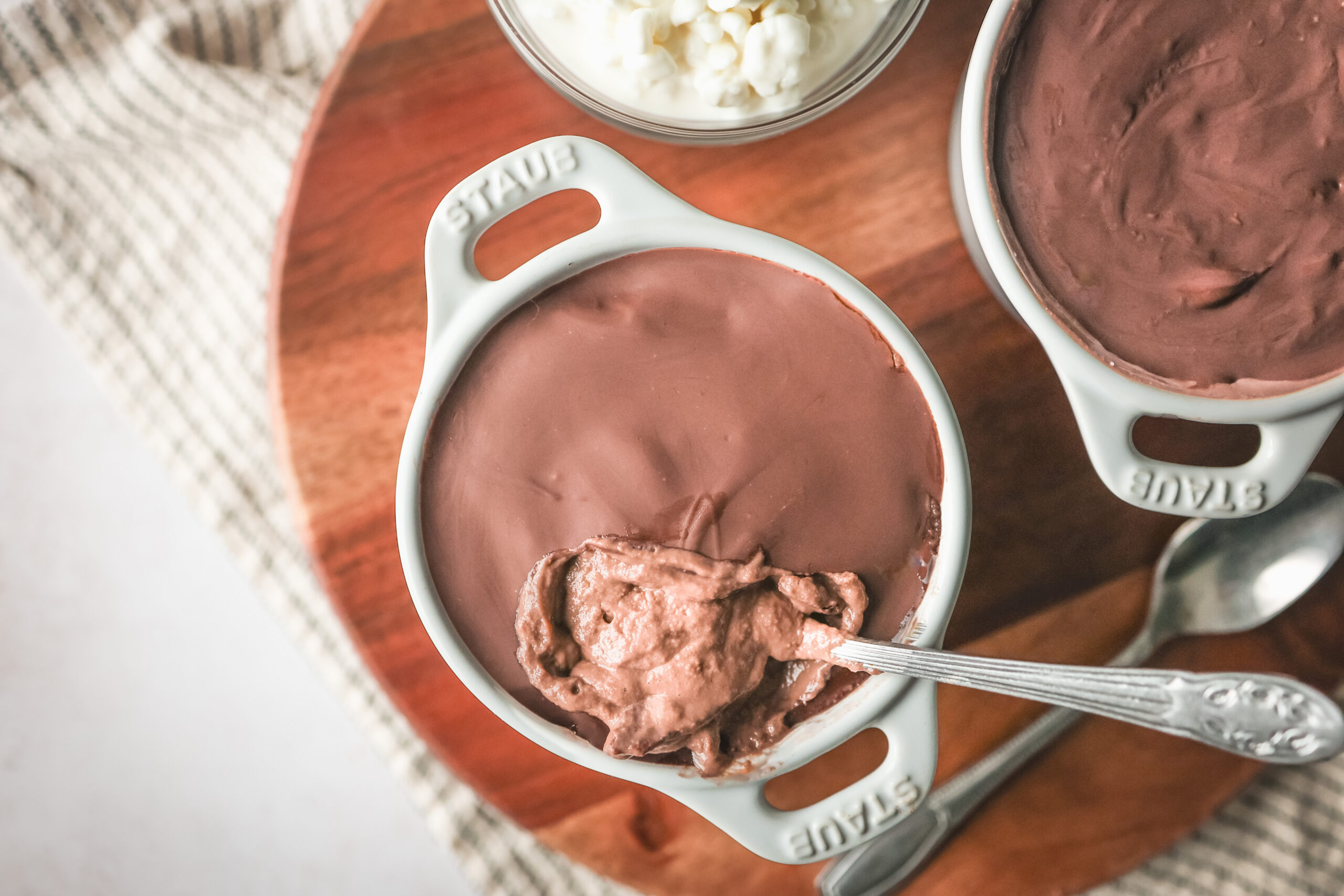 A small bowl of chocolate protein cheesecake with a cracked chocolate shell on top, revealing a creamy cocoa filling underneath.