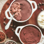 A small bowl of chocolate protein cheesecake with a cracked chocolate shell on top, revealing a creamy cocoa filling underneath.