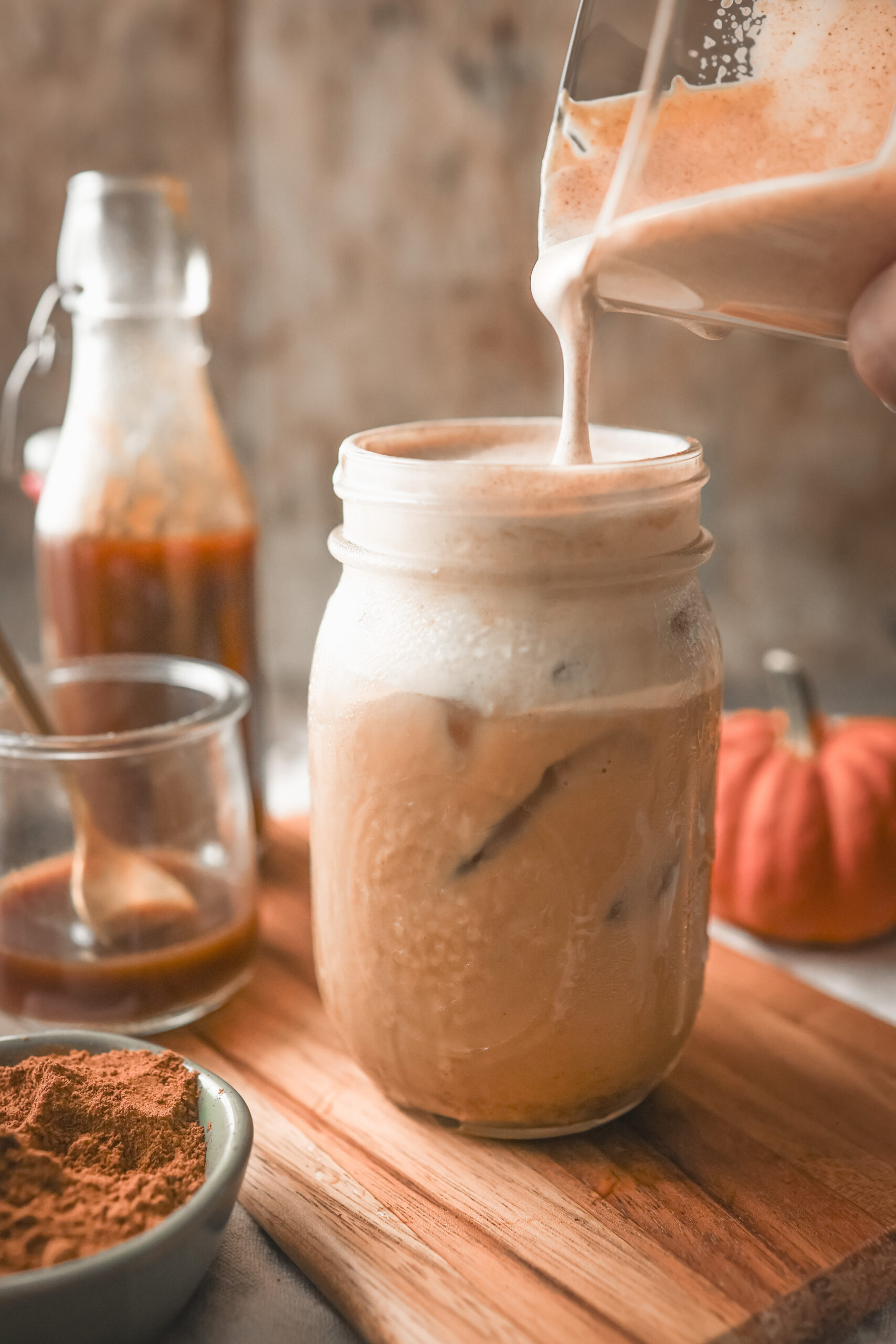 Pumpkin spice cold foam spooned over an iced pumpkin spice latte.